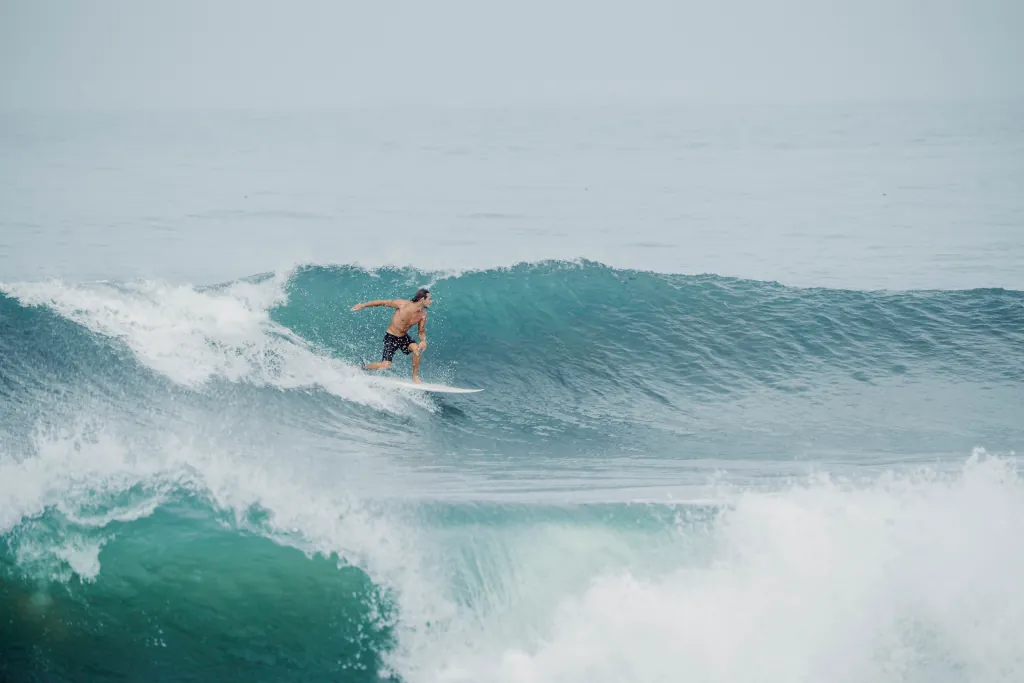Intermediate surfer riding a clean blue wave in Uluwatu Bali