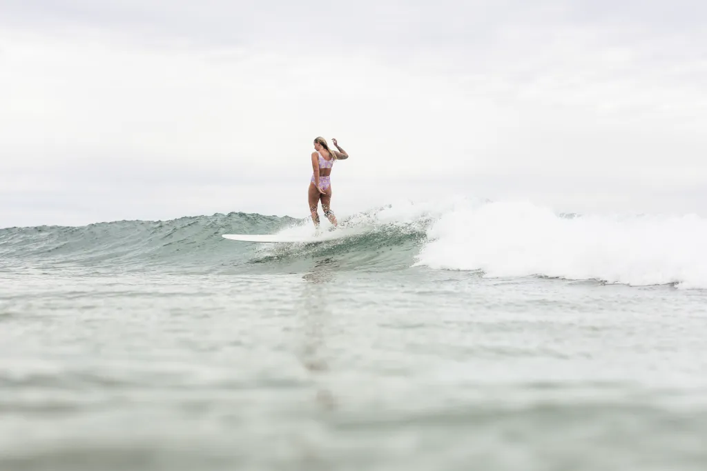 A girl surfing a smaller wave on a longer board