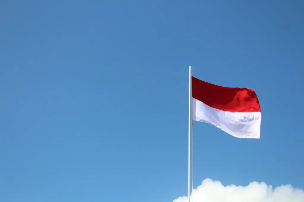 Red and white flag flying underneath a blue sky in the daytime