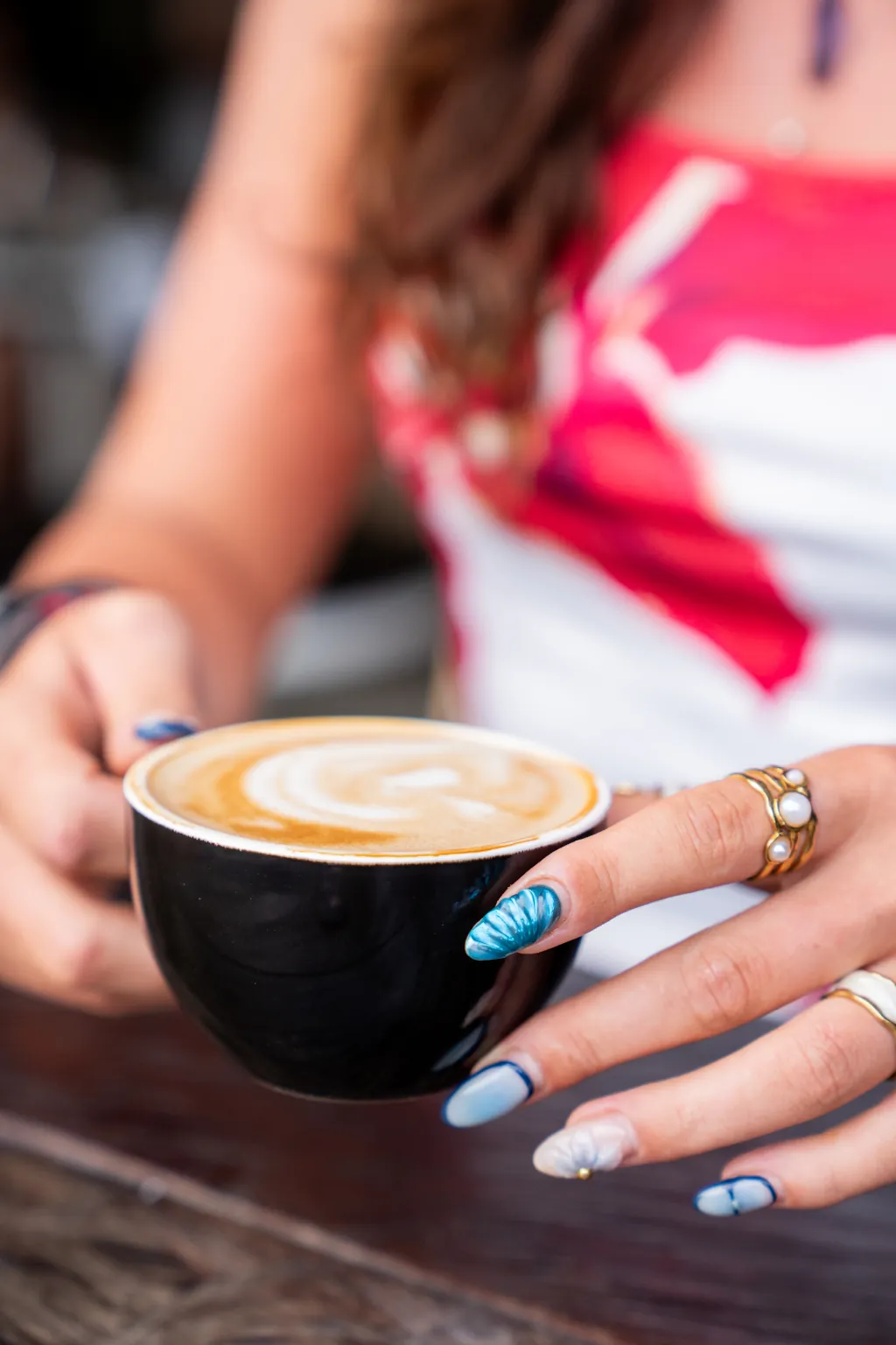 A woman holding a cappuccino in her hands