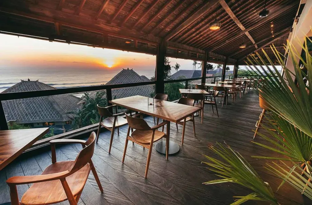 dining tables on a wooden deck overlooking the surf and indian ocean below at sunset