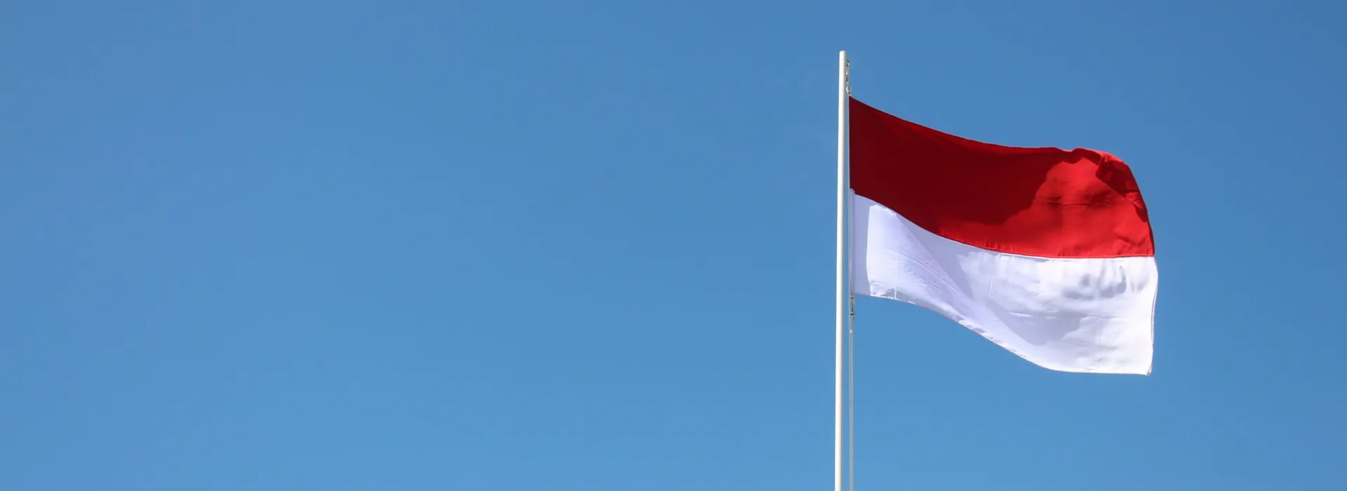 red and white flag under a blue sky in the daytime