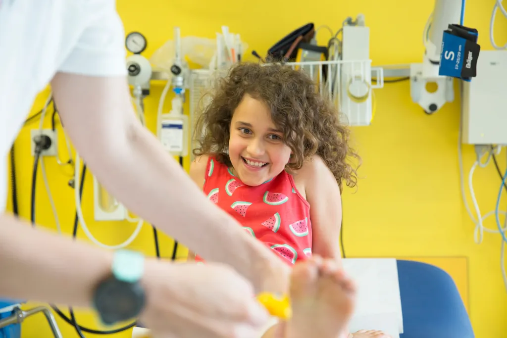 a girl smiling at the camera sitting on a doctors bed