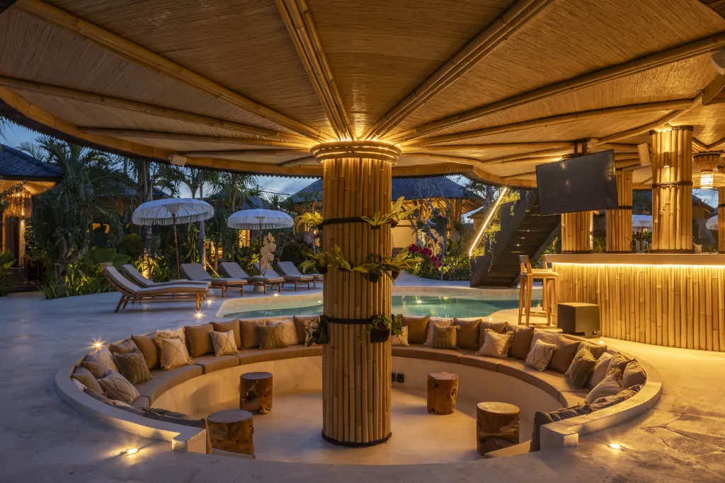 A shared space at night with the main pool and a sunken lounge.