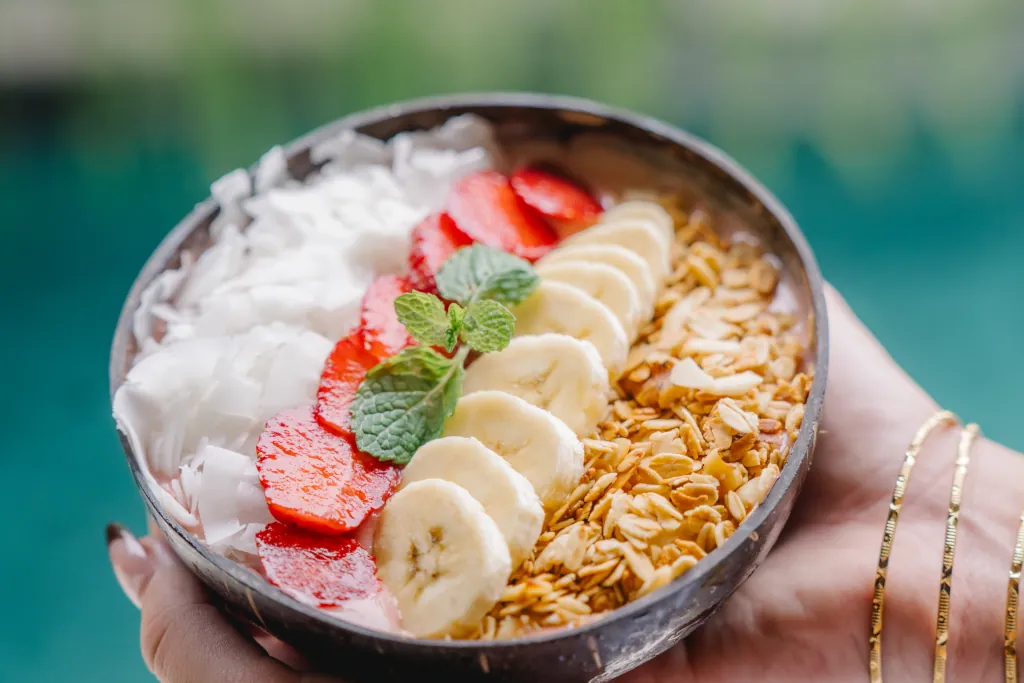 A strawberry smoothie bowl with coconut flakes and granola on top