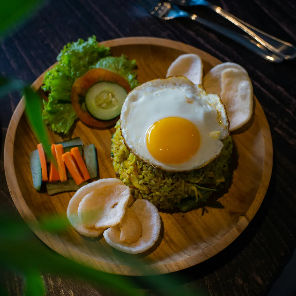 mie goreng on a wooden plate with a sunny side up egg