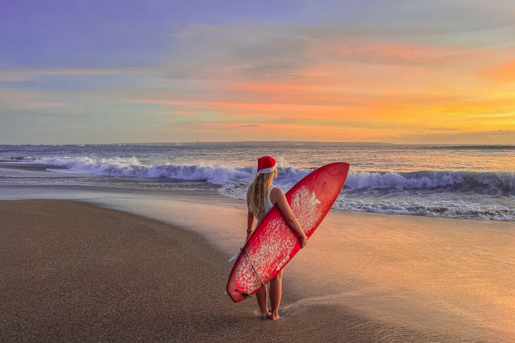 A GIRL HOLDING A RED SURFBOARD DURING A BEAUTIFUL SUNSET