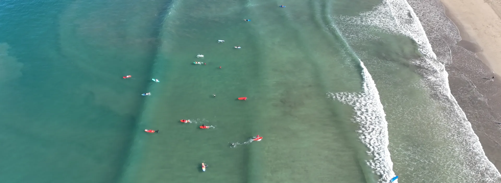 A drone shot of beginner surfers on a wave