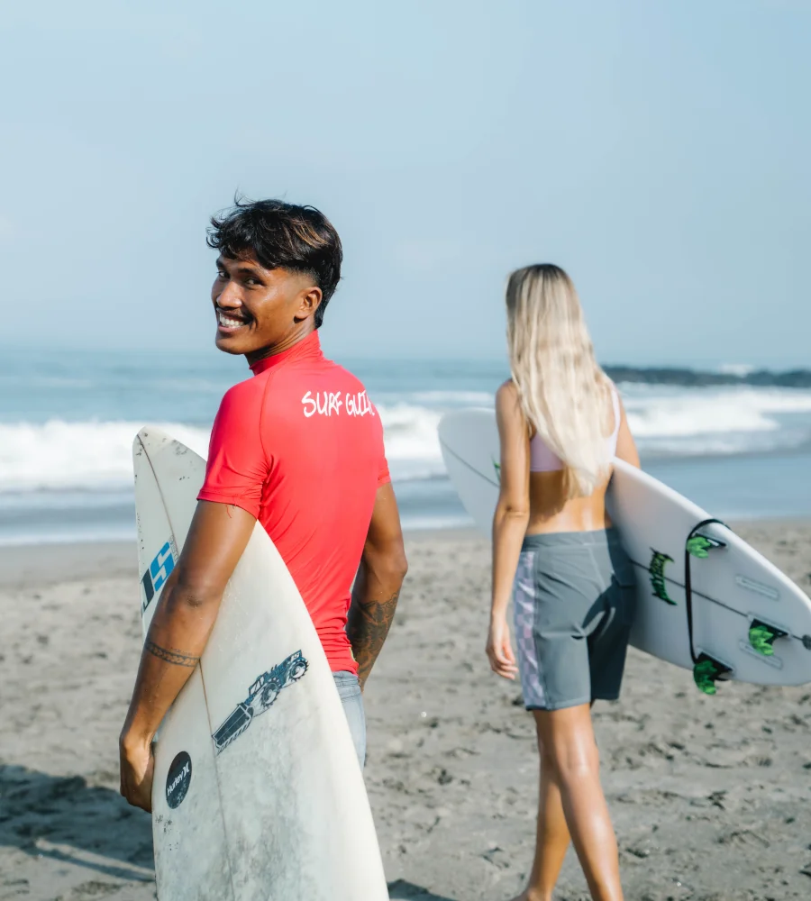 A surf guide and their student entering the ocean