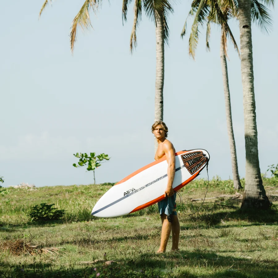 A male surfer holding an AIPA surfboard