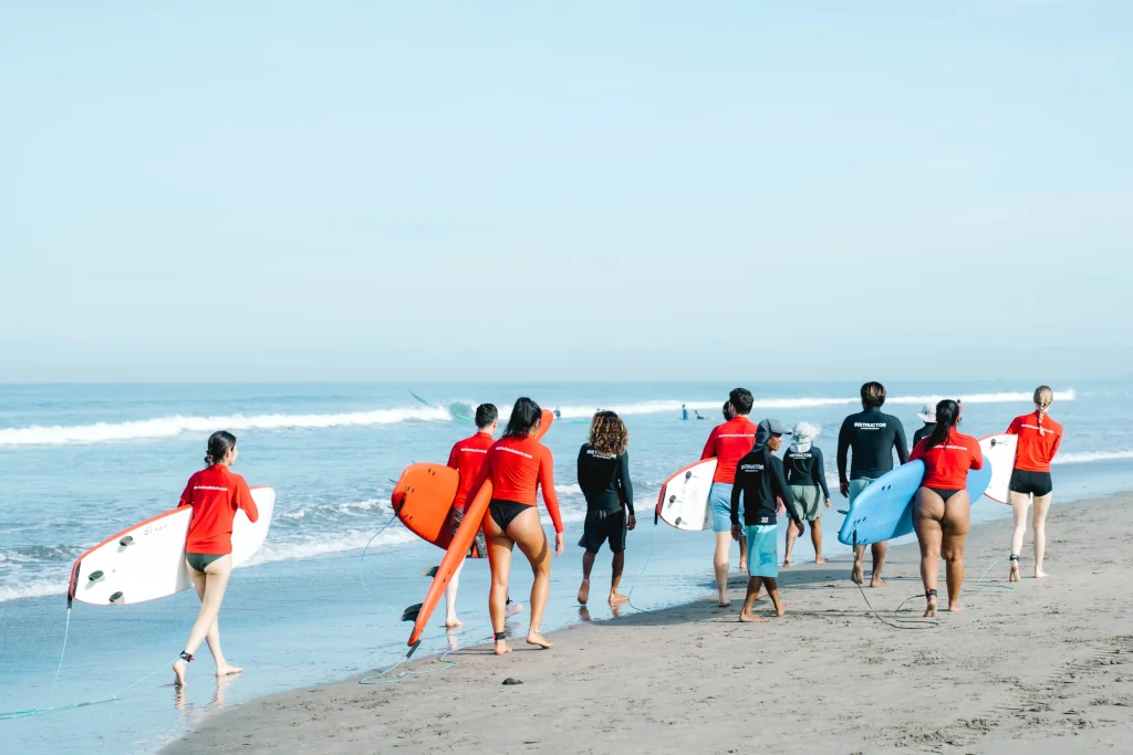 a group of people walking with their backs to the camera holding soft top surf boards