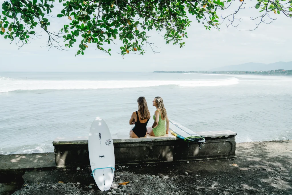 two girls sitting and watching the surf