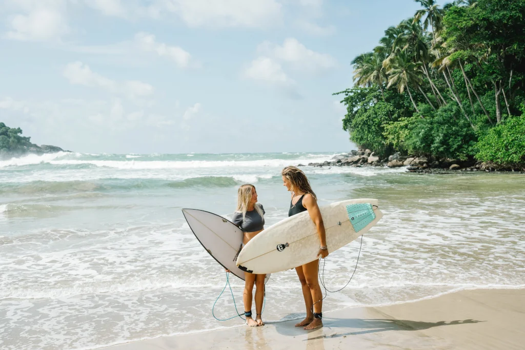two young girls holding surfboards on the beach
