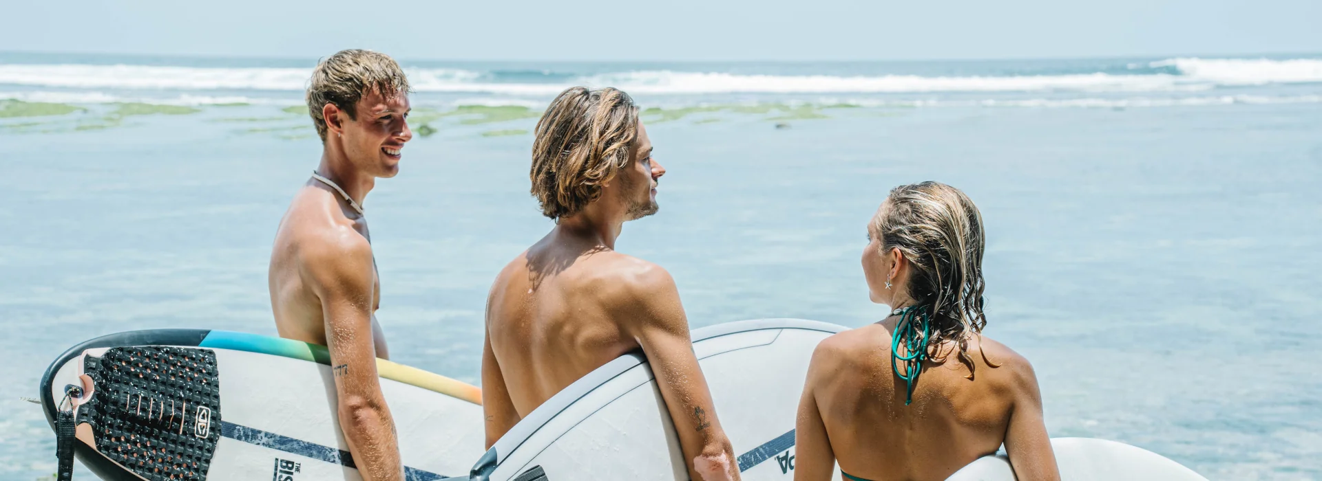 a group of surfers walking on the beach with their boards