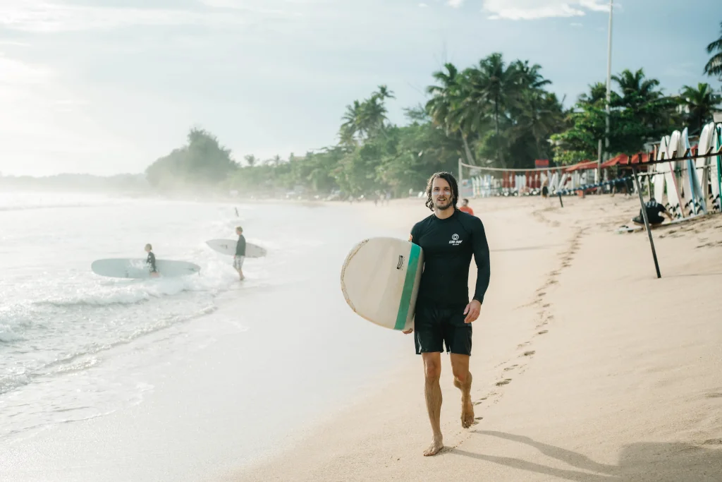 A surfer holding a hard-top surfboard
