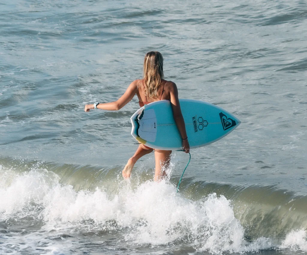 A woman walking out holding her surfboard