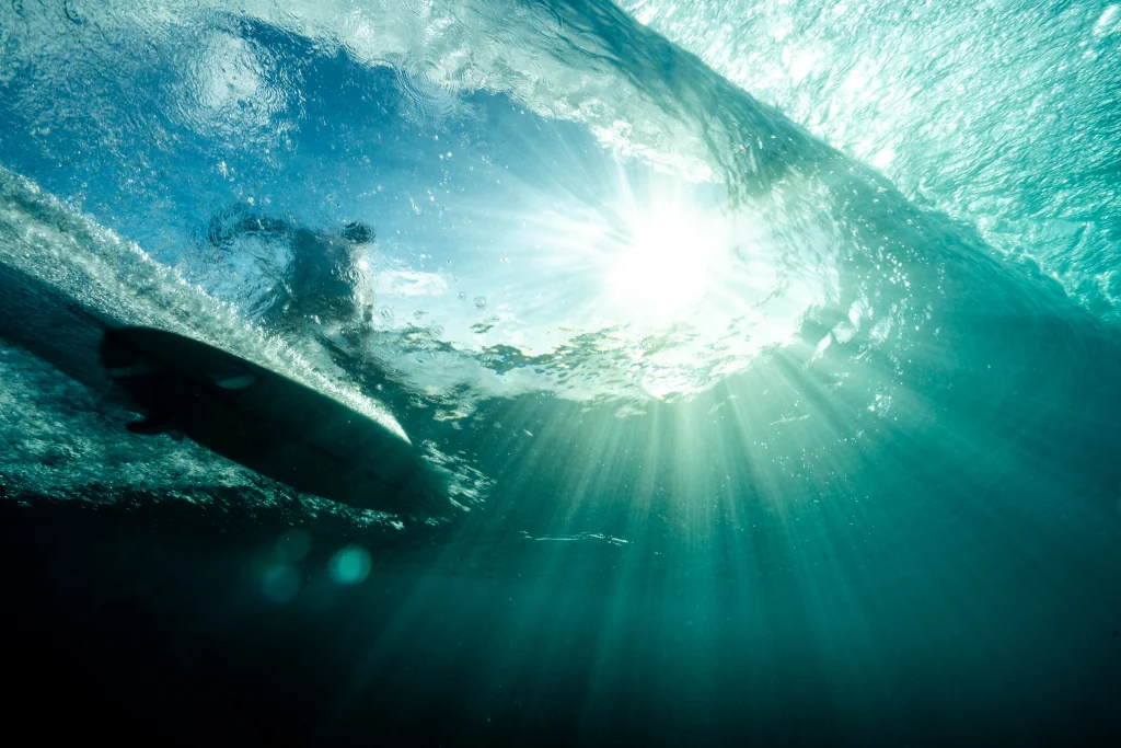 A man surfing a wave from below the ocean POV