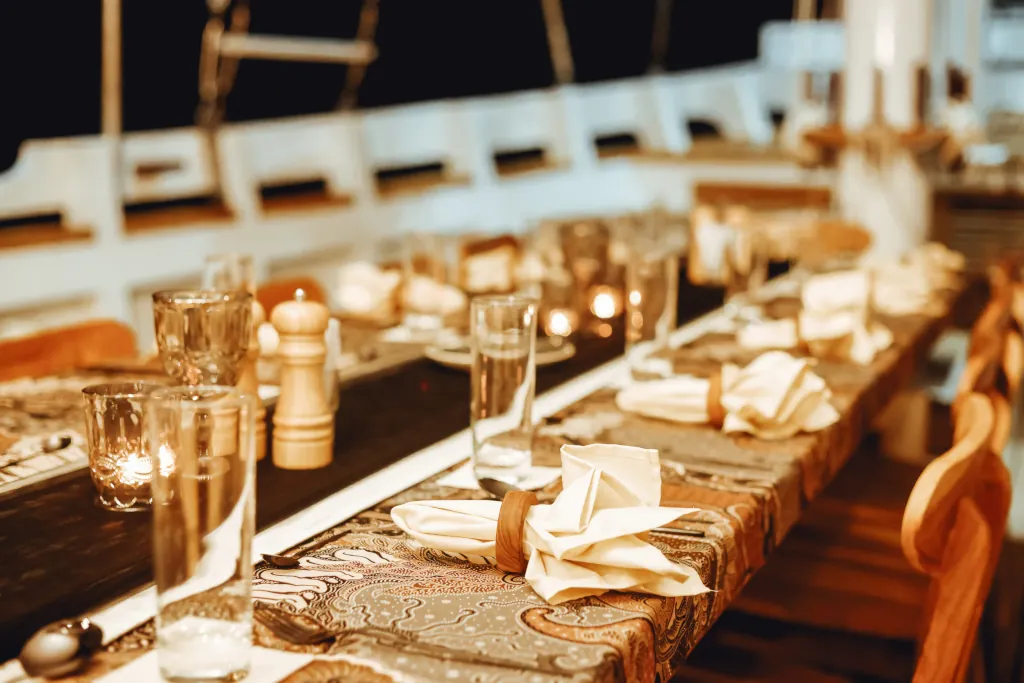 A long dinner table set up with cutlery, glasses and fine dining decoration