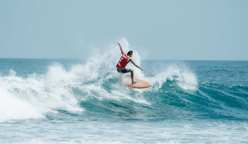 A pro surfer doing a surf maneuver on a left hander wave.