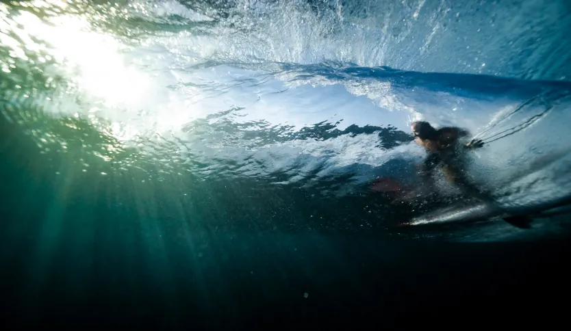 A surfer riding a barreling wave, the photo is taken from the perspective of being inside the wave.