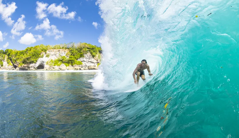 Ein professioneller Surfer macht einen Front-Side-Snap mit einem großen Wasserspray an einem berühmten Surf Break in Uluwatu, Bali